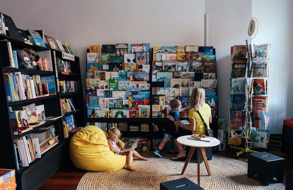A mother and children enjoy reading in a colorful library section with diverse book selections.