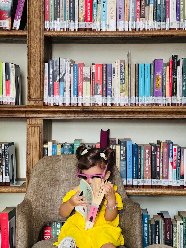 Adorable child in yellow dress reading a book in a colorful library in Istanbul.