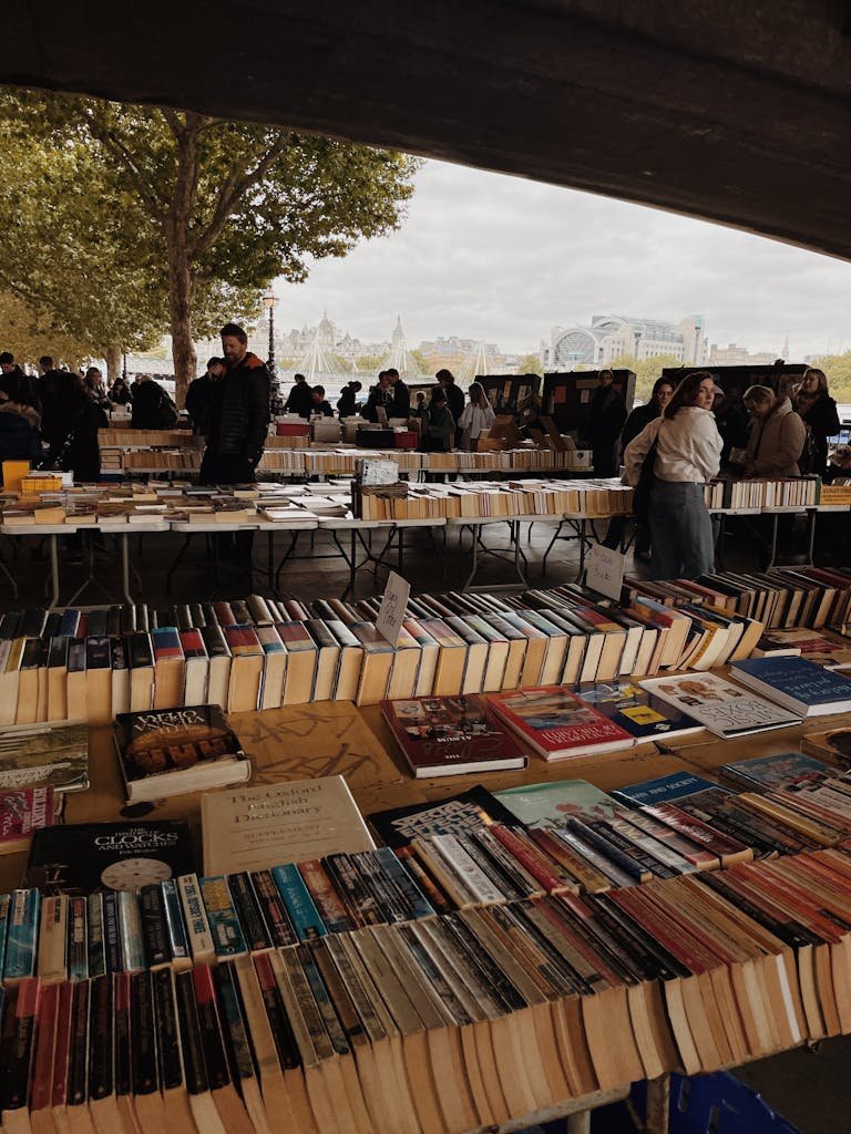 An outdoor book market with tables of books and numerous shoppers enjoying a lively atmosphere.